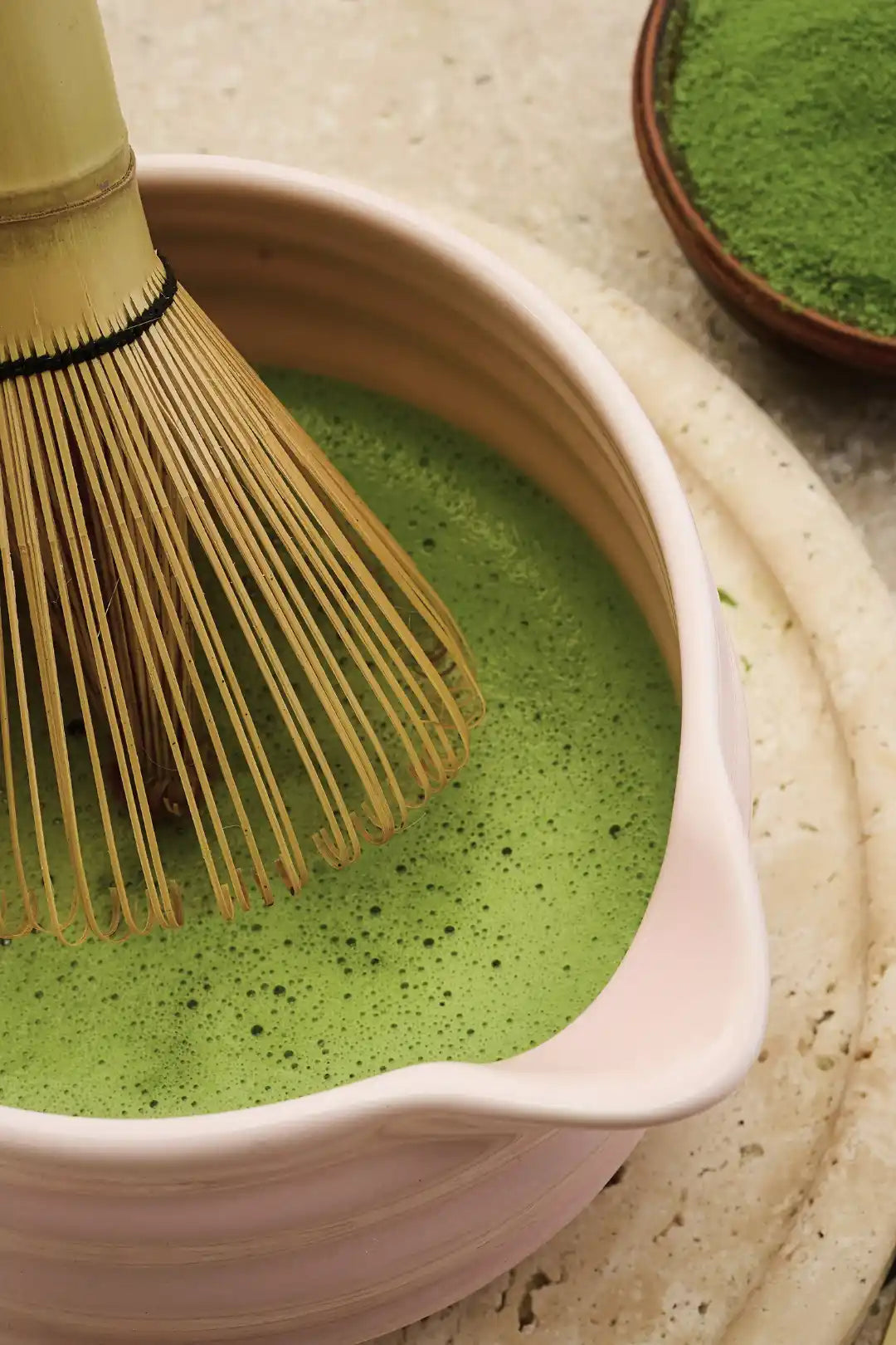 KAIA Origin matcha ritual close-up, premium powder whisked with bamboo chasen in ceramic bowl
